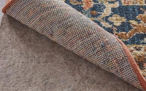 A thick felt rug pad with the corner of a rug folded back over it