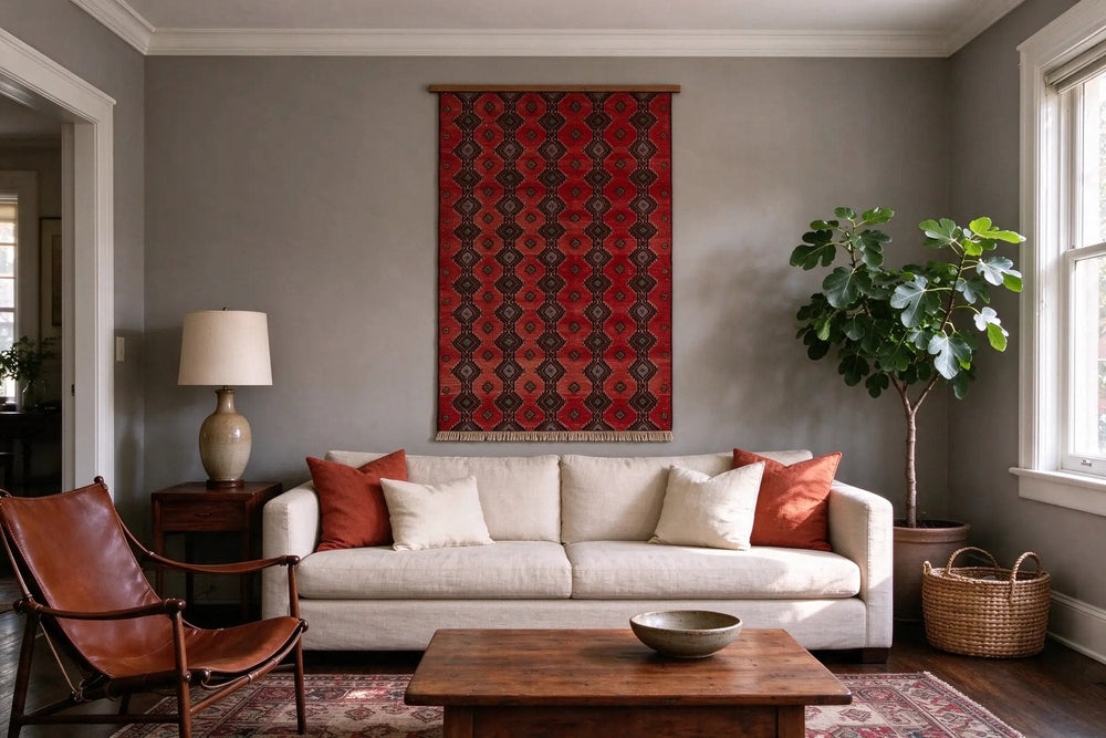 Warm gray living room, a small deep red Baluch rug hung from its short end on a wooden batten above a linen sofa