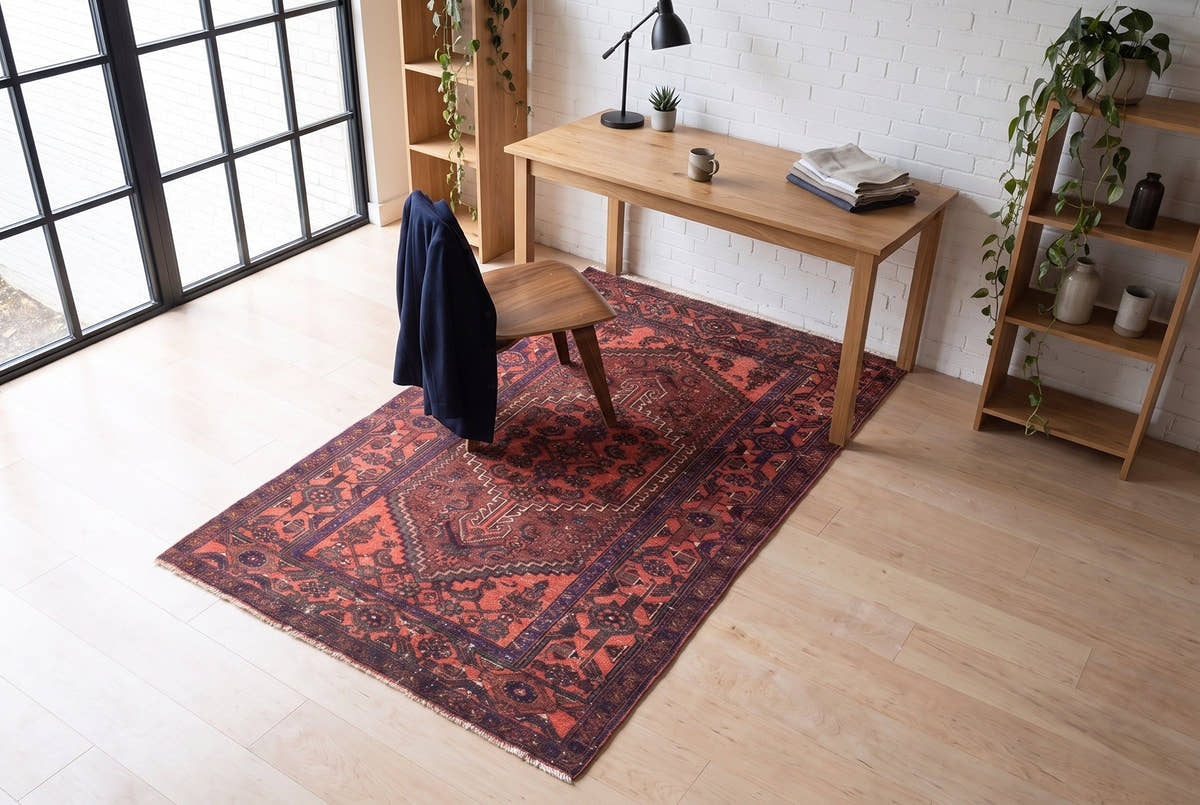 A coral-red vintage Persian Zanjan rug in a workspace in a converted 1910s factory loft in Liberty Village, Toronto, seen from above