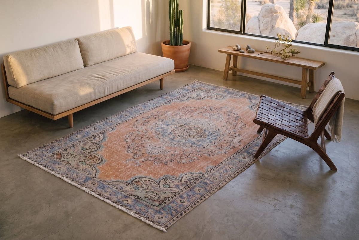 A faded orange vintage Turkish Manisa rug seen from above in a small desert house near Joshua Tree, California