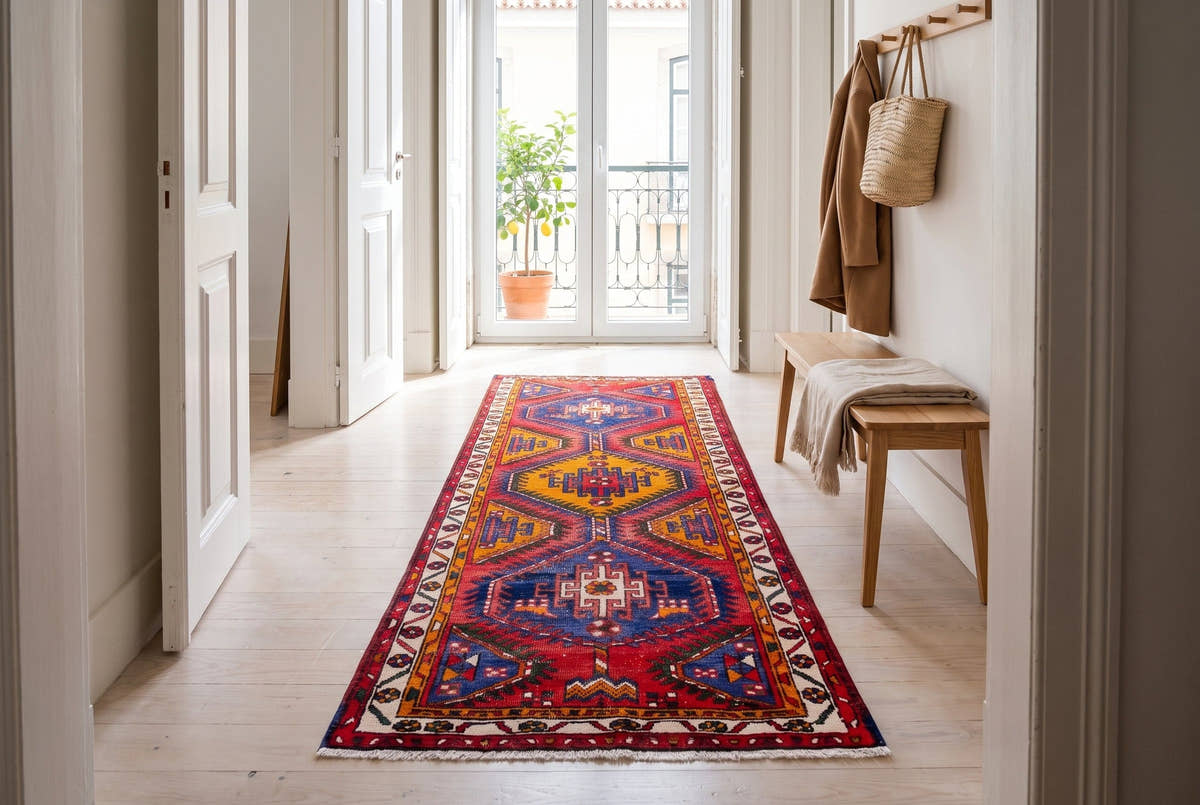 A bright red vintage Persian Azerbaijan runner with blue and gold medallions in a white Lisbon hallway
