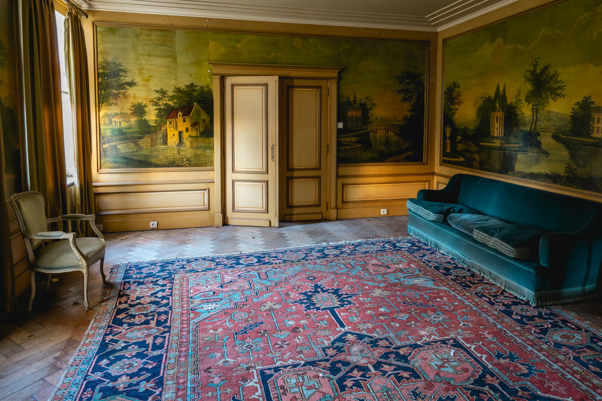 Vintage Persian rug in a panelled drawing room with a teal velvet sofa