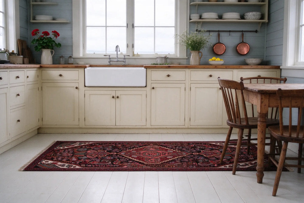 Cottage kitchen with pale blue clapboard walls, a dark red Songhor runner along cream cabinets and a farmhouse sink on white painted boards