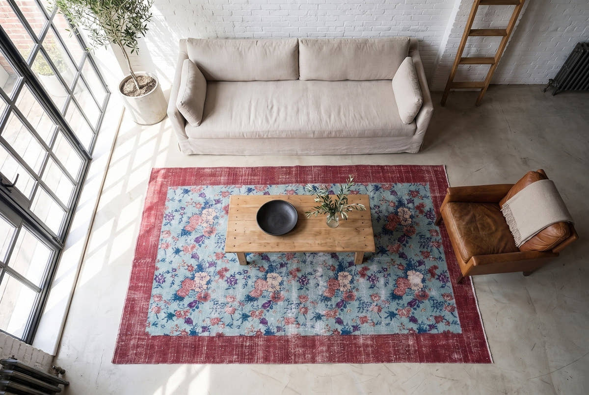 A vintage Turkish Isparta rug seen from above with a pale blue field and red border in a Brooklyn warehouse loft