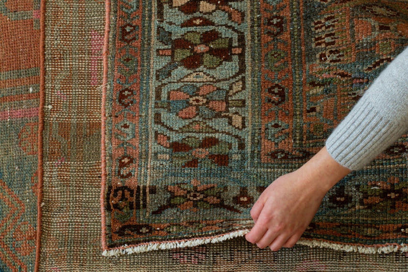 Hand resting on the pile of a hand-knotted vintage rug