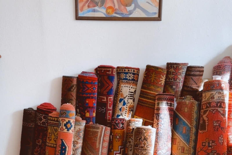 Rolled vintage Persian and Turkish rugs stacked against a wall
