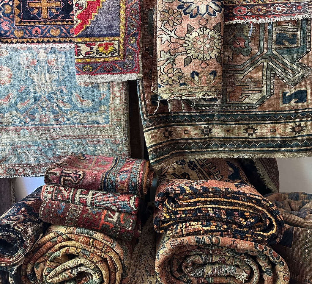 Vintage rugs hanging on brass racks in a showroom